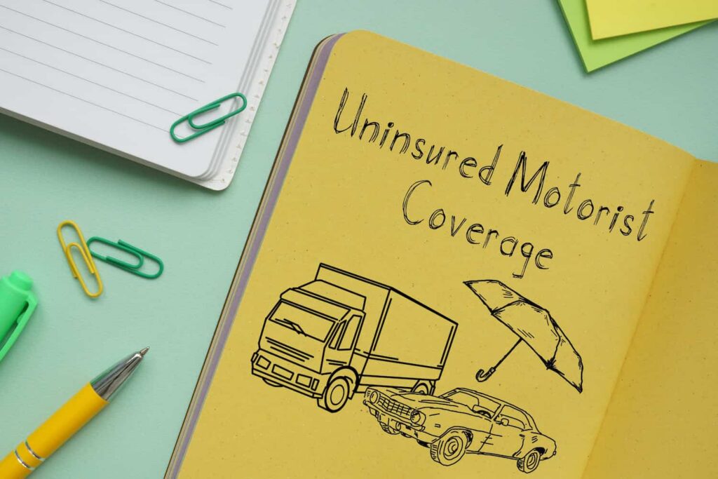 Uninsured motorist coverage concept with notebook illustration of car accident and insurance protection umbrella