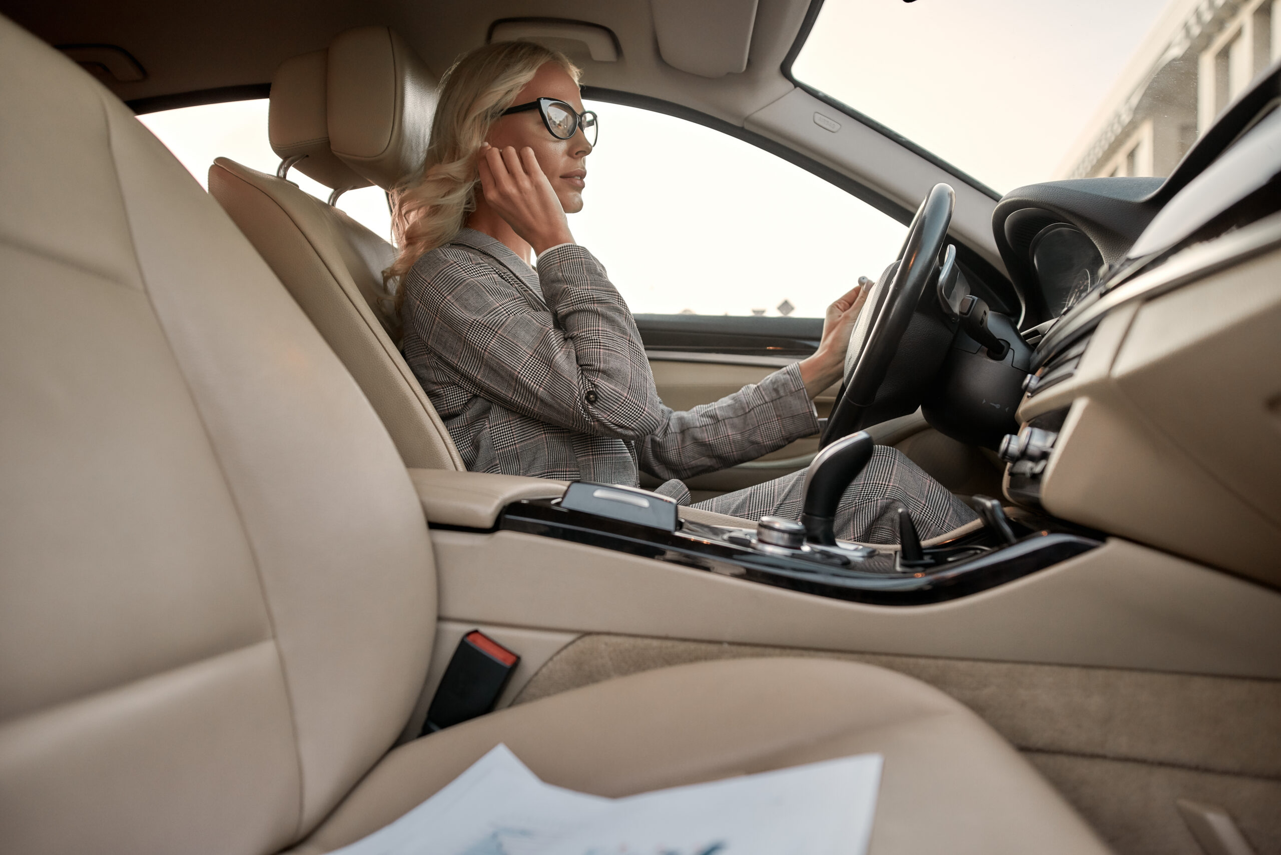 Woman driving car while touching ear representing use of headphones while driving in Texas